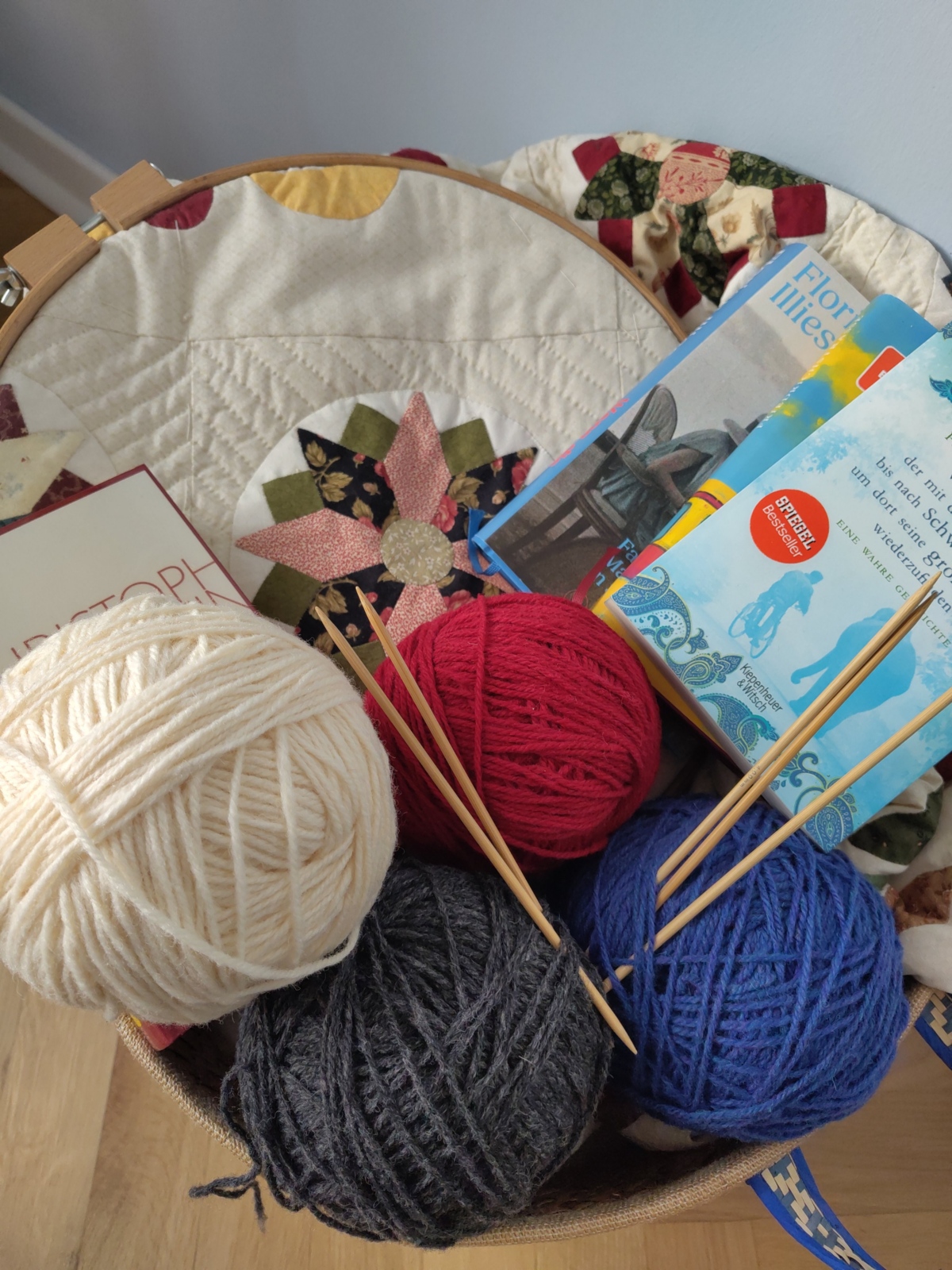 Bücher, Wolle und Stricknadeln auf einer Quiltdecke